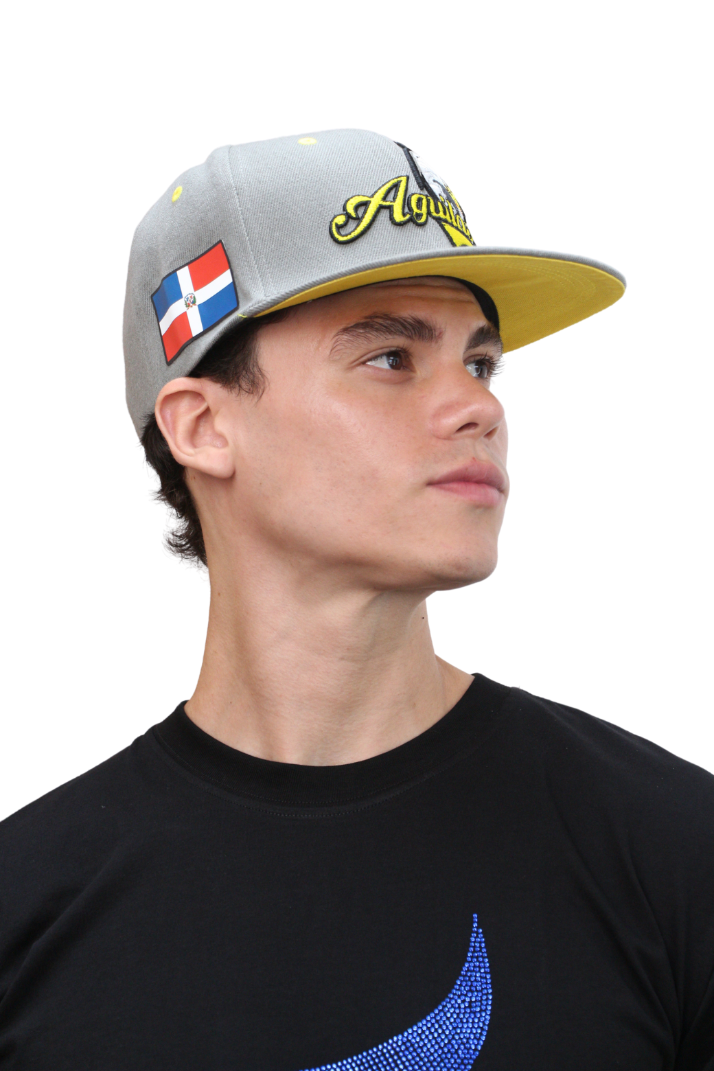 A person wearing a flatbill snapback cap with a grey crown and an embroidered eagle logo. The cap has a yellow brim with a flag emblem on the side. Main image