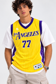 Front view of model wearing the West Coast 77 yellow mesh basketball jersey with script lettering and number 77