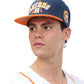 A person wearing a blue and orange snapback cap with 5D and 3D embroidery on it.