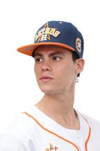 A person wearing a blue and orange snapback cap with 5D and 3D embroidery on it.