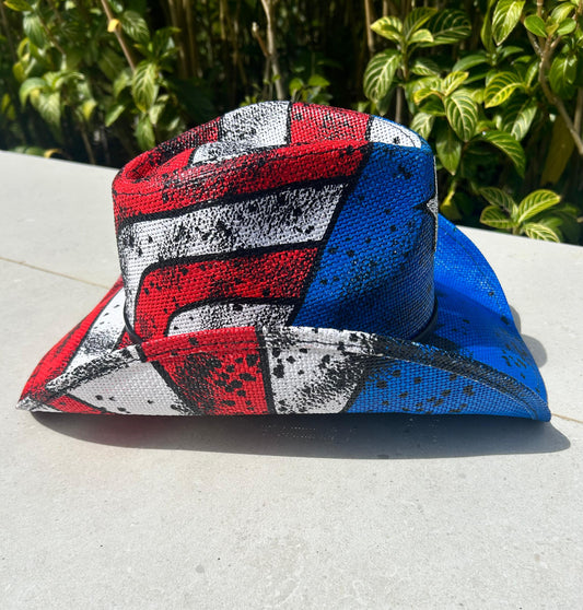 Colorful fabric with red, white, and blue patterns on a light surface with green foliage in the background.