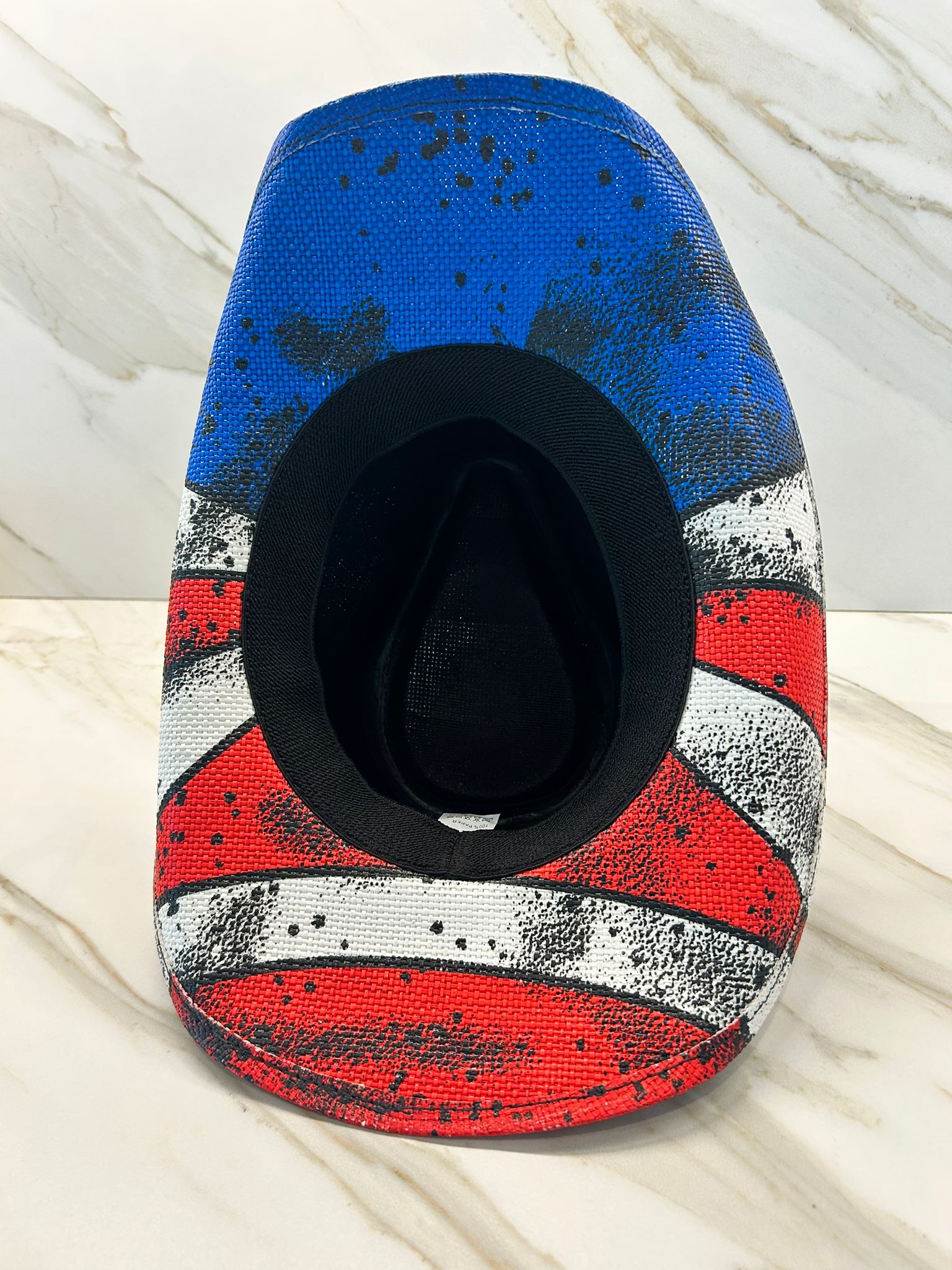 Cowboy hat with a colorful American flag design on a light wooden surface