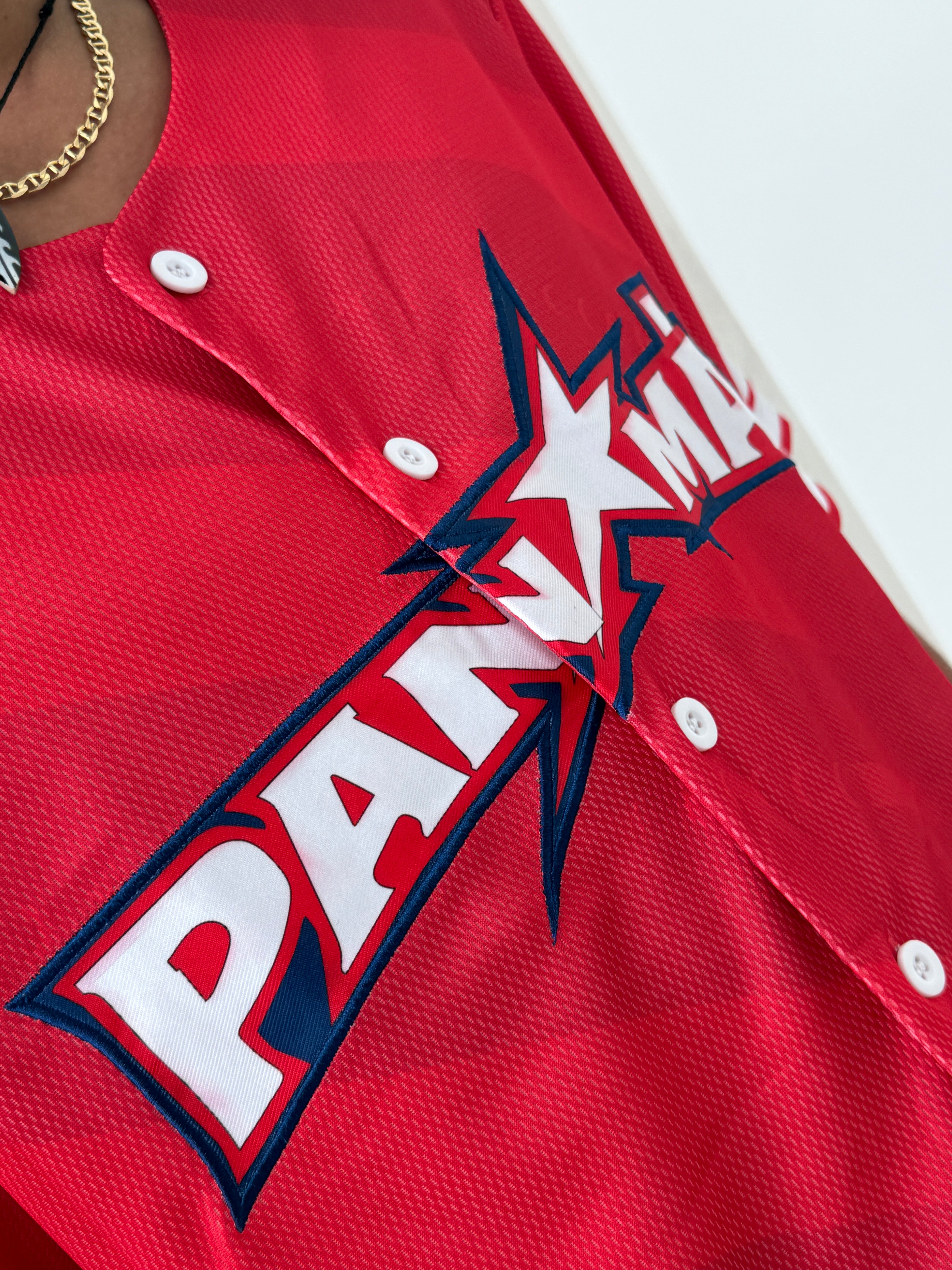 Red baseball jersey with a prominent logo on a white background