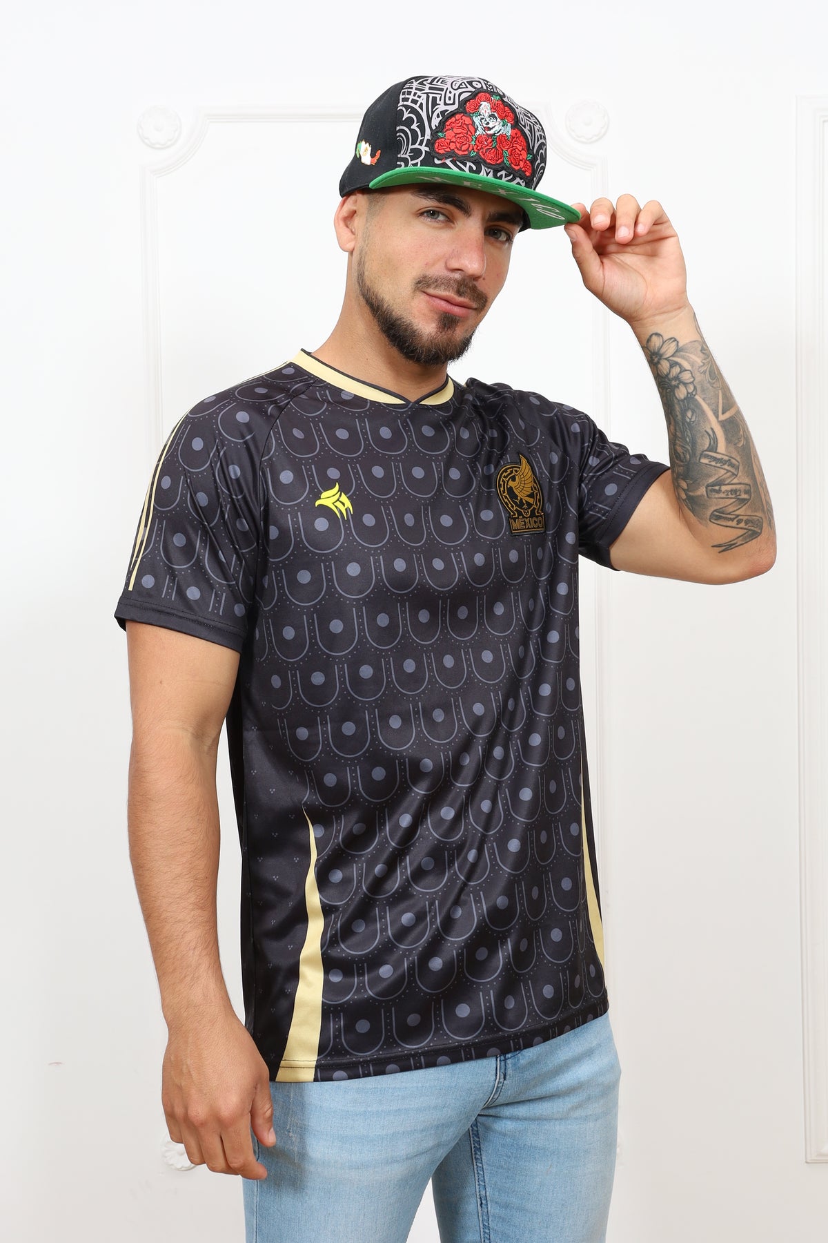 Person wearing a patterned shirt and jeans, holding a cap on a white background