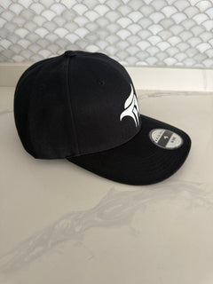 Two black baseball caps with logos on a textured surface