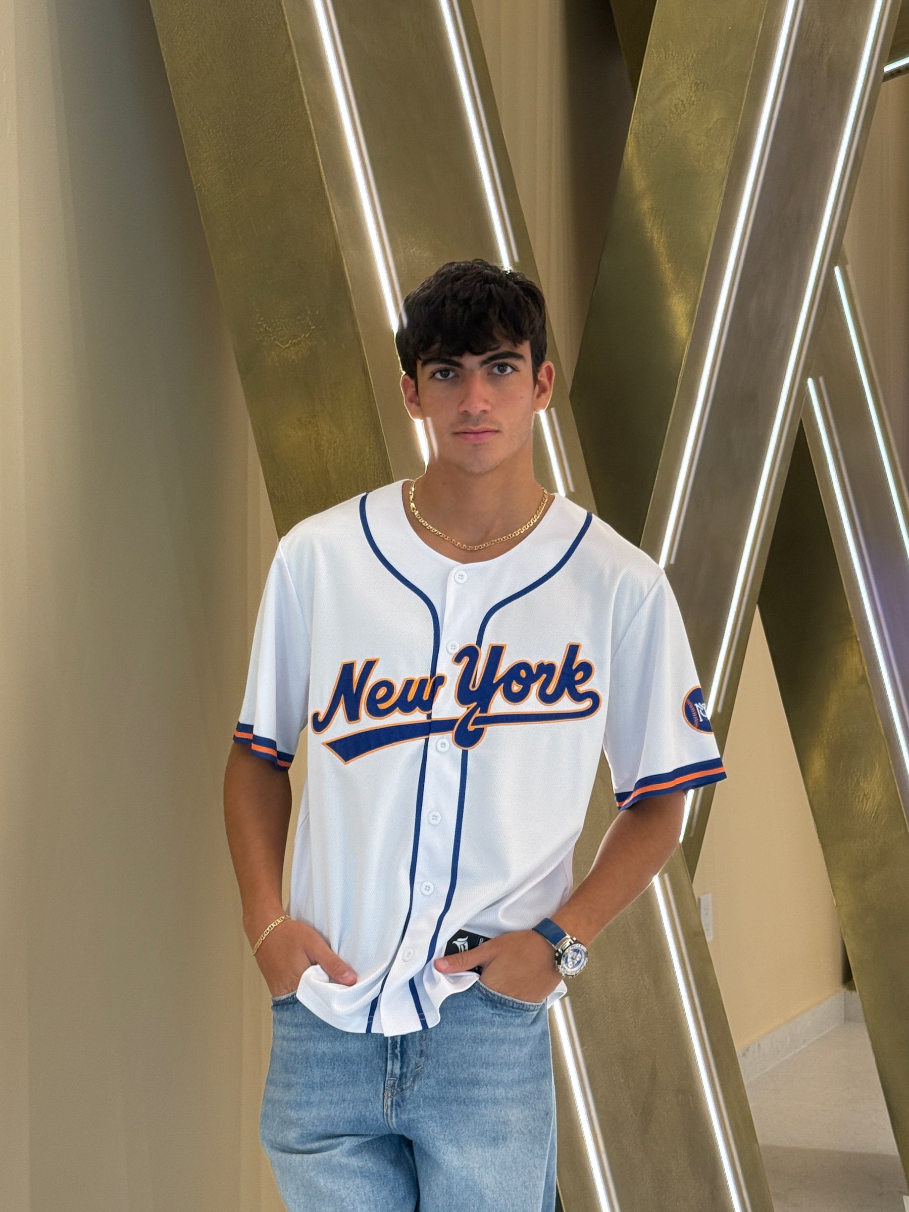 Person wearing a New York sports jersey standing in front of metallic beams.