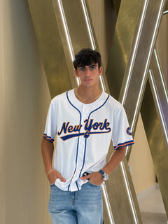 Person wearing a New York sports jersey standing in front of metallic beams.