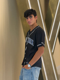 Person wearing a black 'New York' t-shirt with a gold geometric background