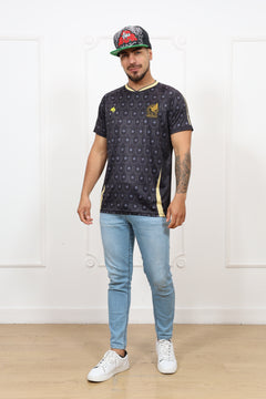 Person wearing a dark patterned shirt with logos, light blue jeans, and white sneakers on a white background.