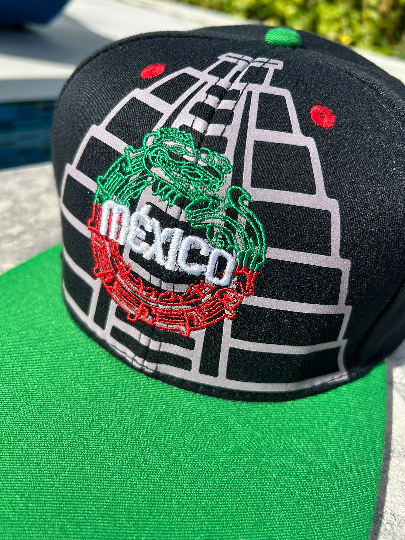 A black structured cap with embroidered Maya pyramids and Quetzalcoatl snake, featuring the Mexican map and coat of arms on the sides, red vent holes, and a flatbill with sublimated symbols. Main image