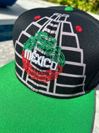 A black structured cap with embroidered Maya pyramids and Quetzalcoatl snake, featuring the Mexican map and coat of arms on the sides, red vent holes, and a flatbill with sublimated symbols.