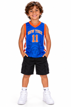 Young boy wearing the New York 11 kids basketball jersey in blue with orange NEW YORK lettering and number 11, black shorts and white sneakers on a white studio background