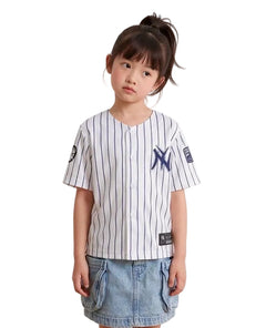 Young girl wearing the white pinstripe New York kids baseball jersey with navy NY logo and denim skirt on a white background