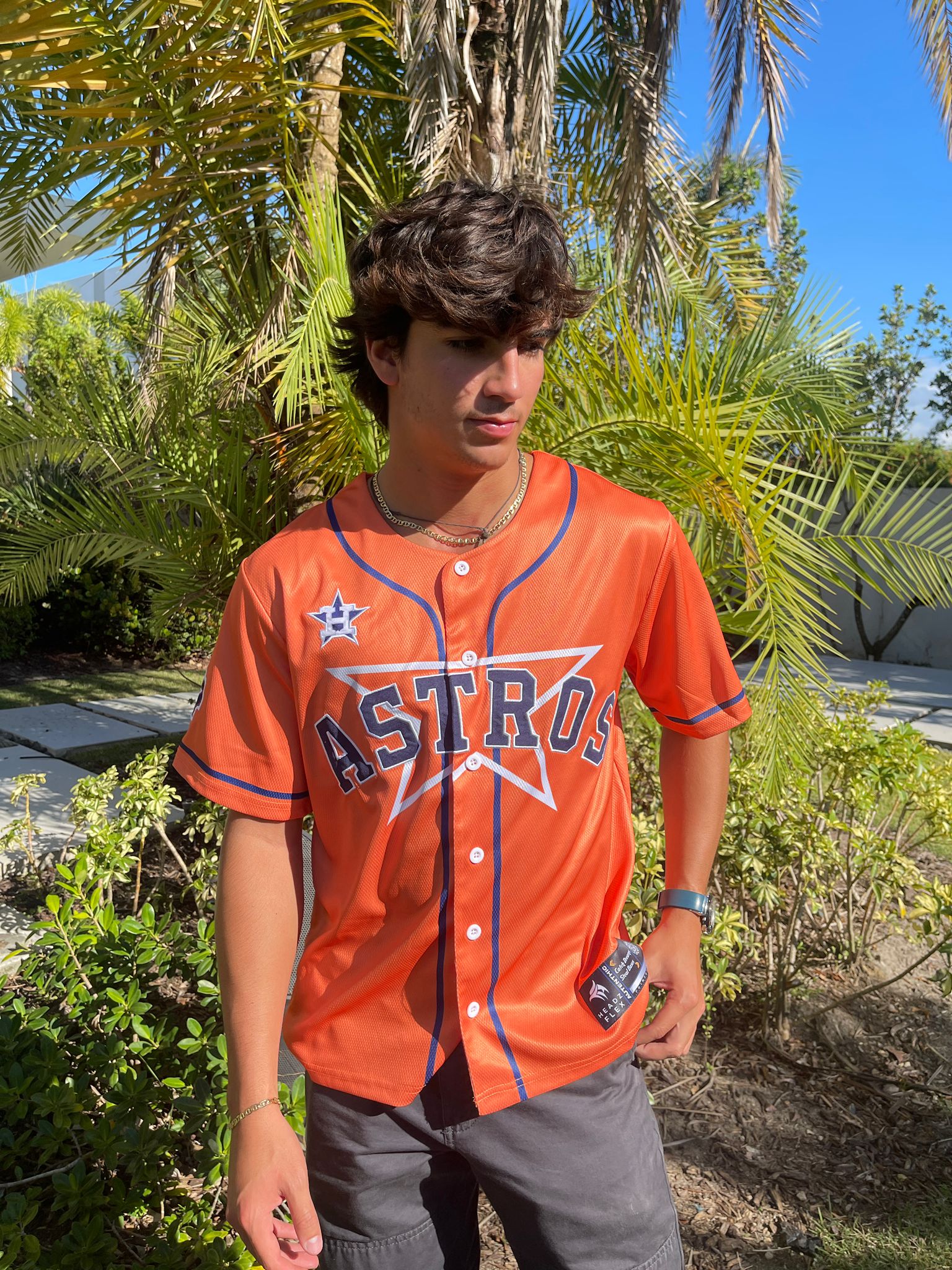 Person wearing an Astros baseball jersey standing outdoors with greenery in the background