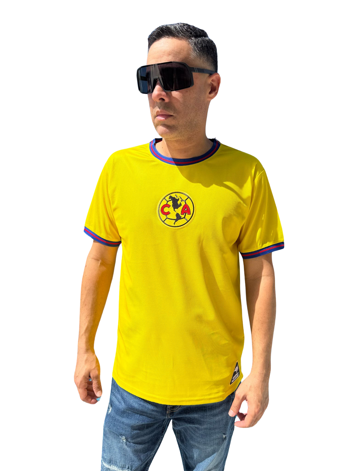 A person wearing a yellow Club America soccer jersey with blue details and a logo on the chest. The jersey has short sleeves, and the person is also wearing sunglasses and blue shorts.