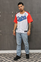 A person wearing a red and white Cuba baseball jersey with vibrant colors and embroidery, paired with blue jeans.