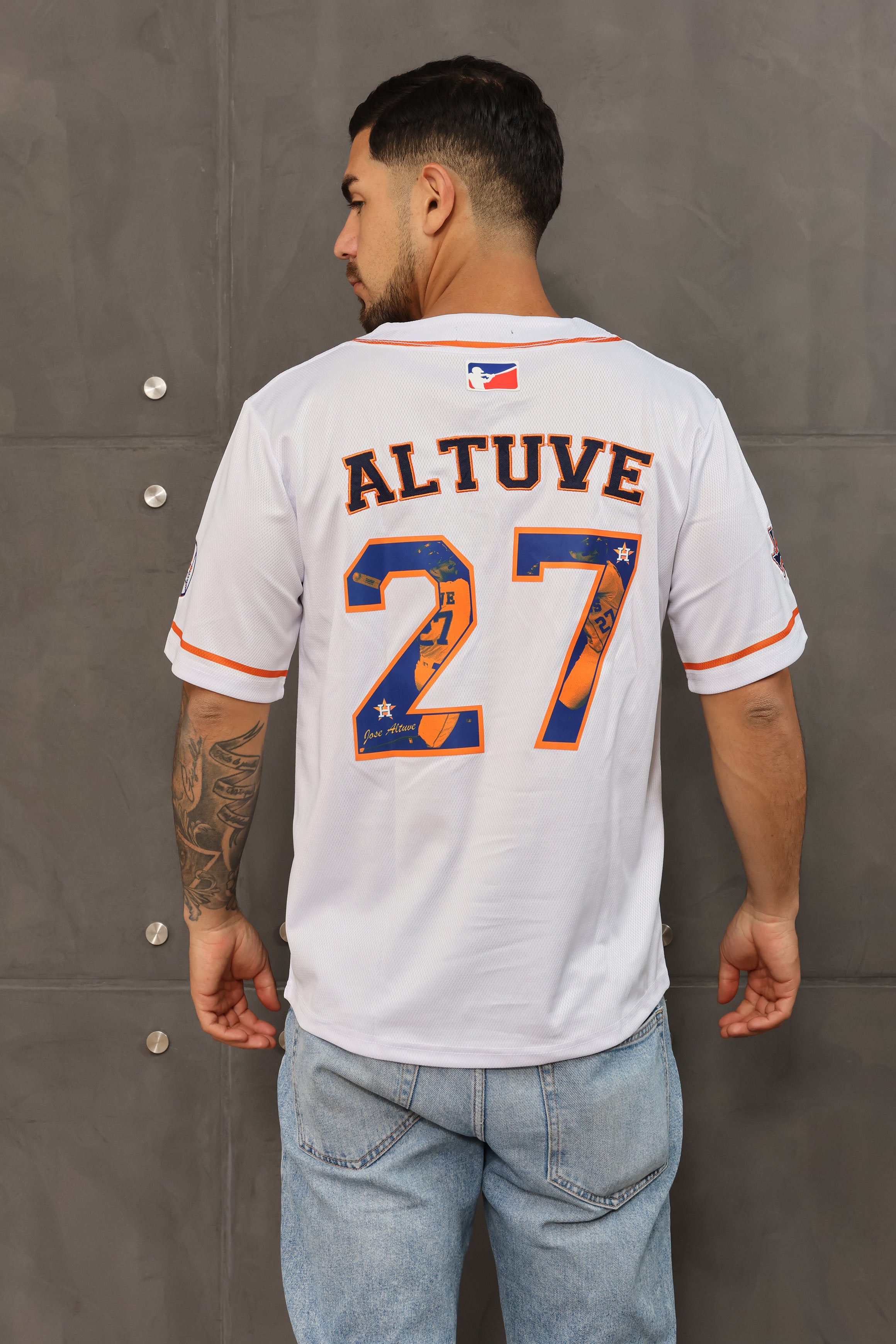 A person wearing a white V-neck, short-sleeve baseball jersey with 'ALTUVE 27' embroidered on the back in orange and blue, representing the Houston Astros. Main image