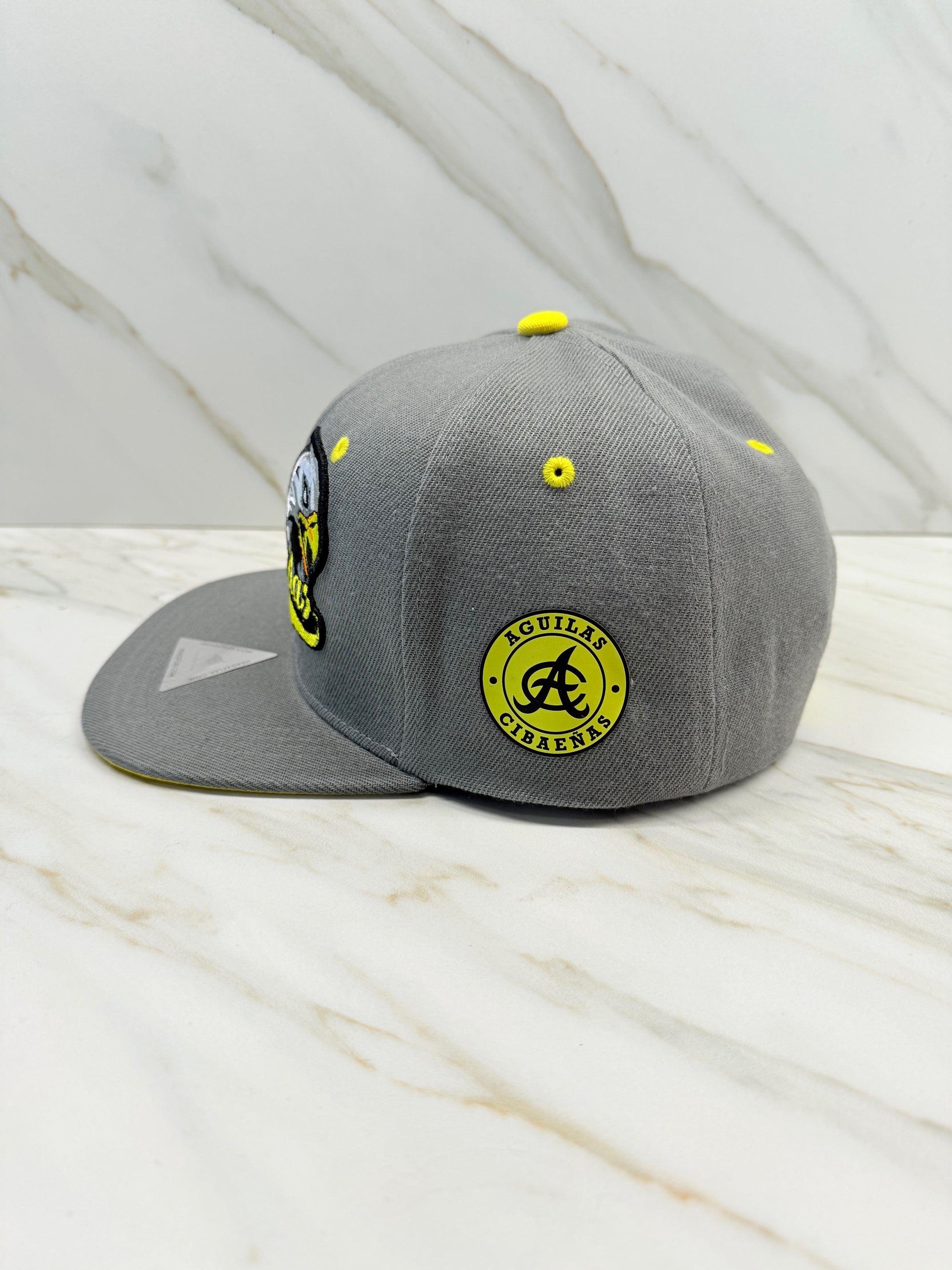 Side view showing Águilas Cibaeñas logo patch on gray snapback cap

