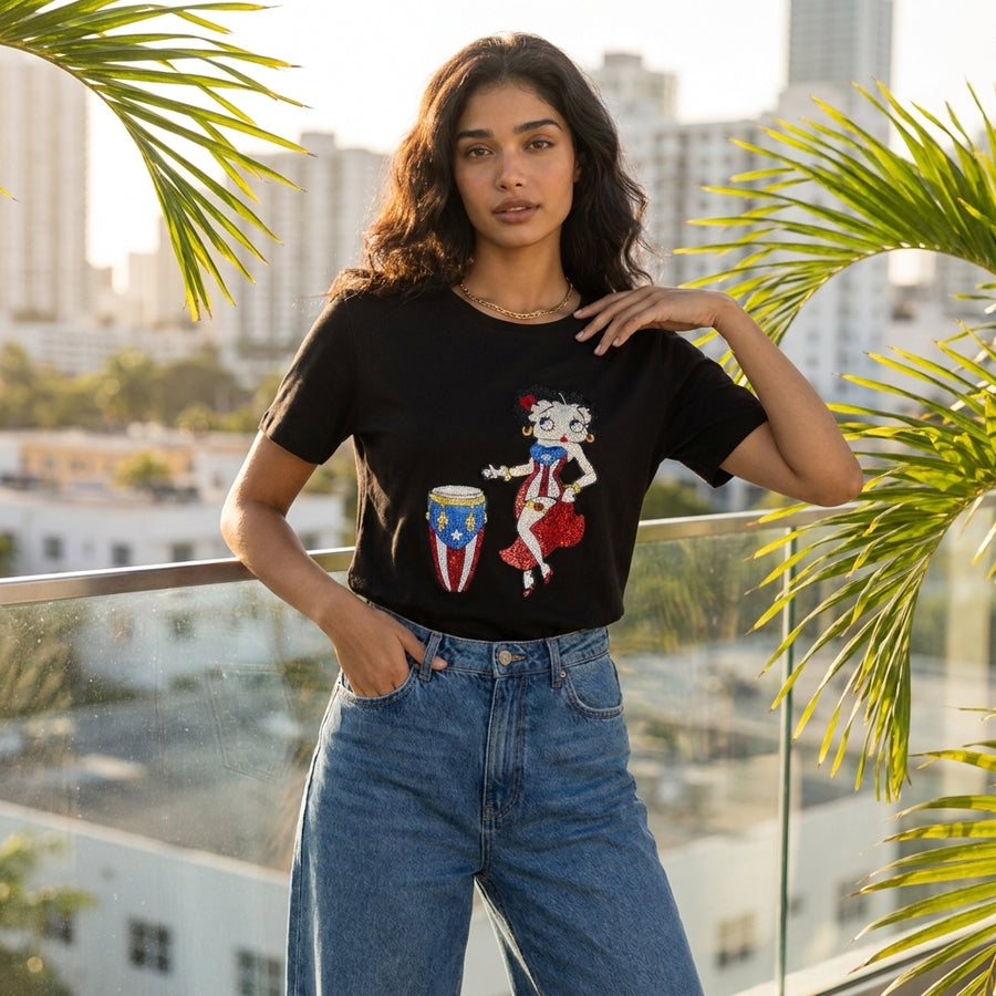 Woman wearing a black t-shirt with a graphic design, standing on a balcony with cityscape in the background.
