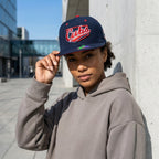Person wearing a navy blue cap with 'Cubs' logo and gray hoodie outdoors.