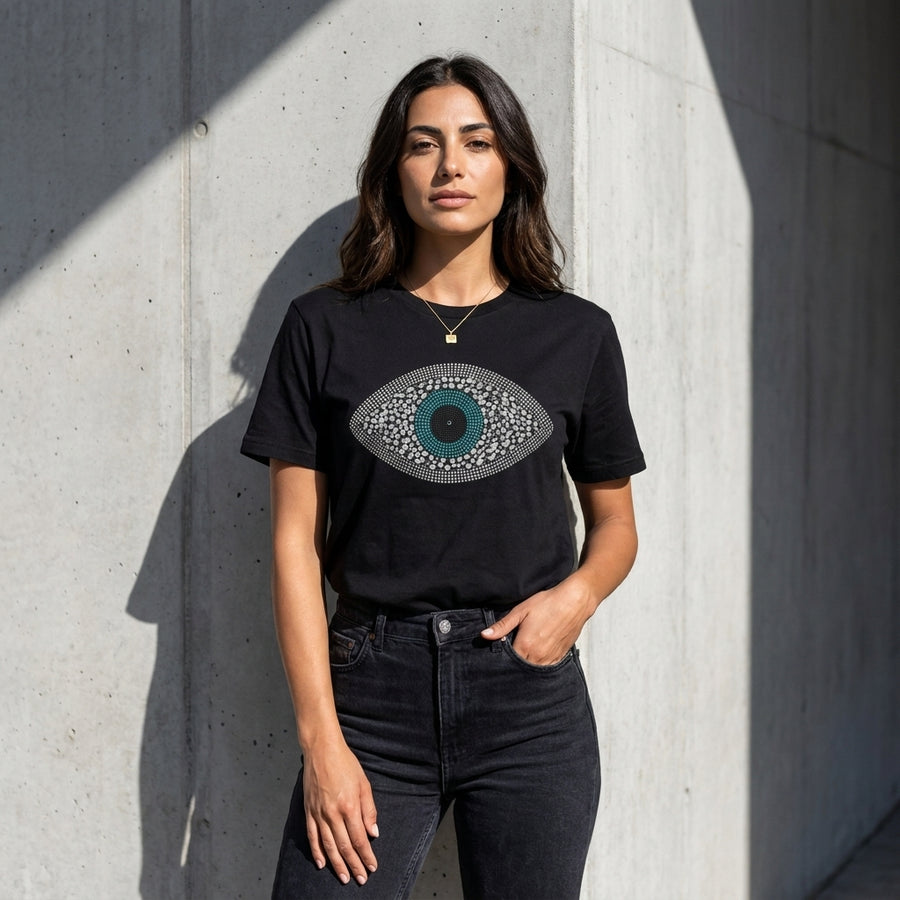 Woman wearing a black t-shirt with a graphic design against a concrete wall.