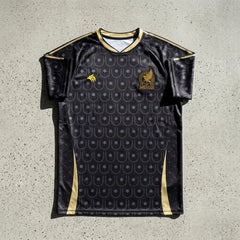 Black sports jersey with gold accents on a gray surface